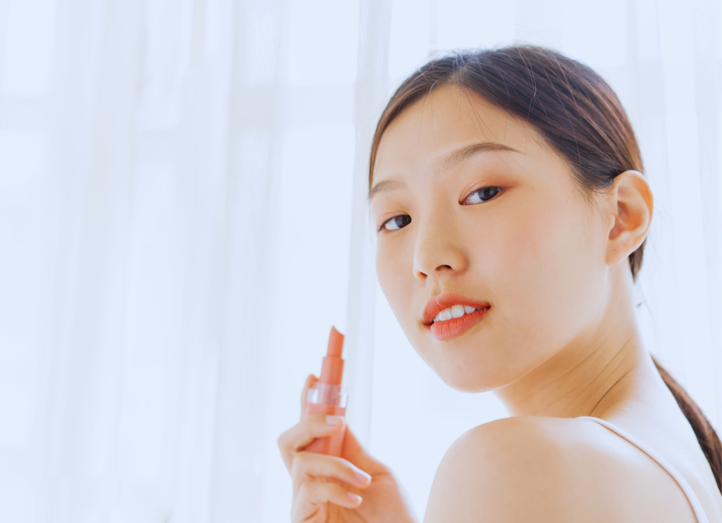 「自信を引き出すKATE」挿入画像。リップを片手にこちらを見る女性。髪を
結んでいる。