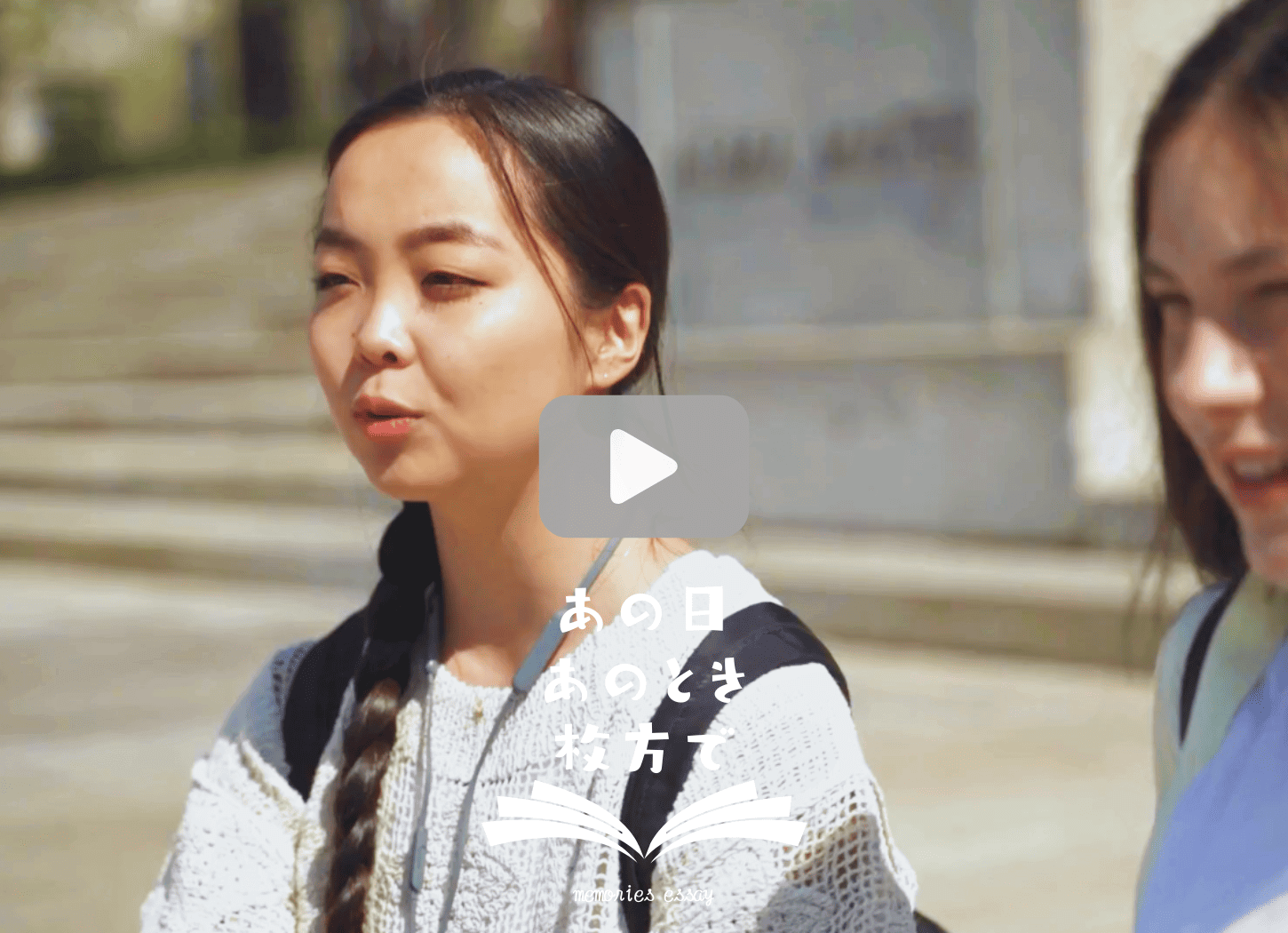 二人の女子が道路で立ち話をしている様子。クリックすると動画が再生されます。