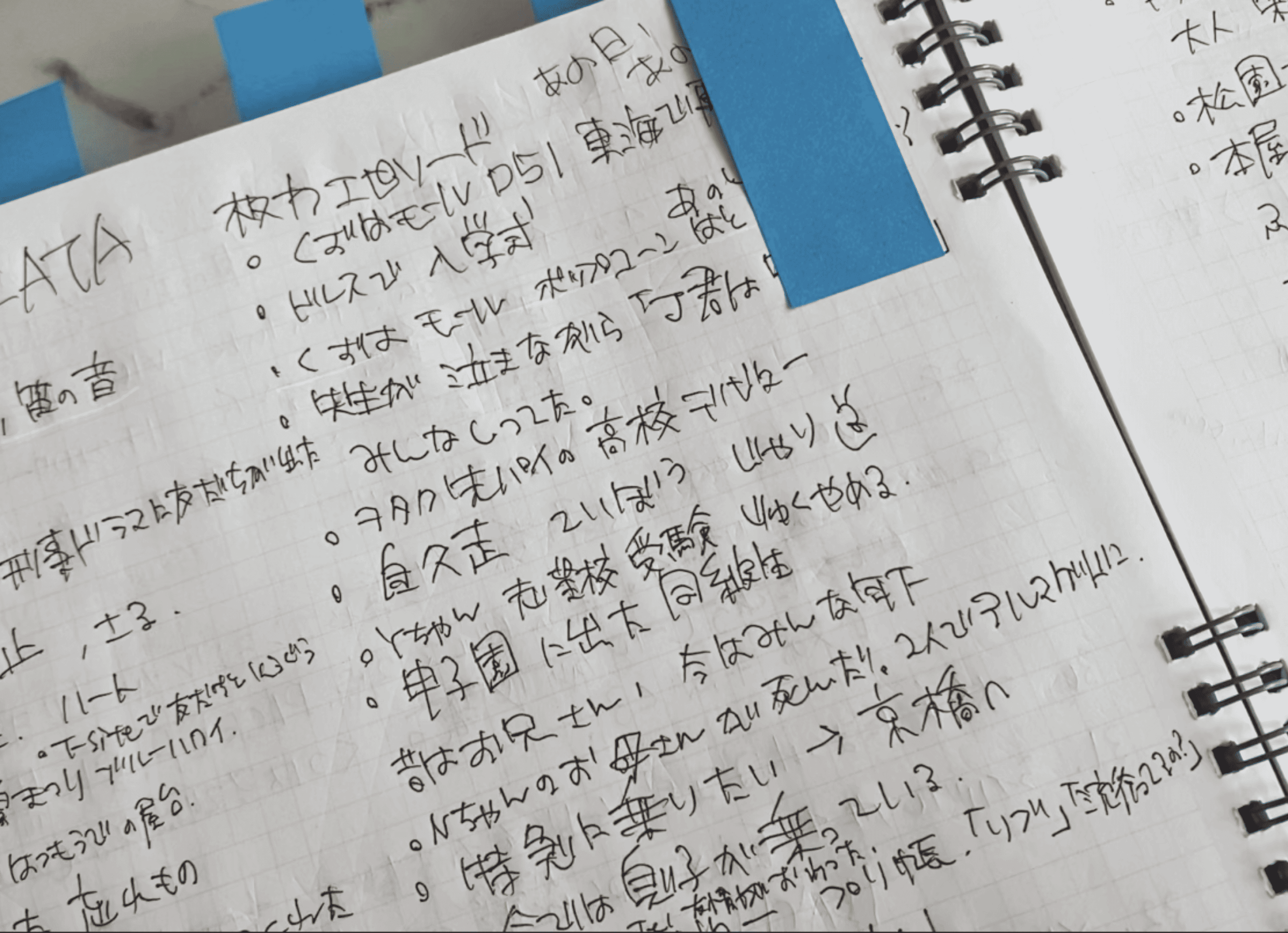 大理石柄のテーブルに置かれた企画ノート。手書きで枚方の思い出がびっしり書き込まれ、青い付箋が貼られている。
