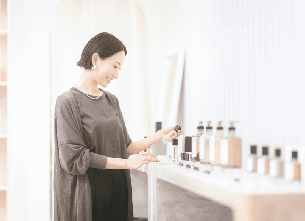 棚にフレグランスやボディーソープを並べる女性