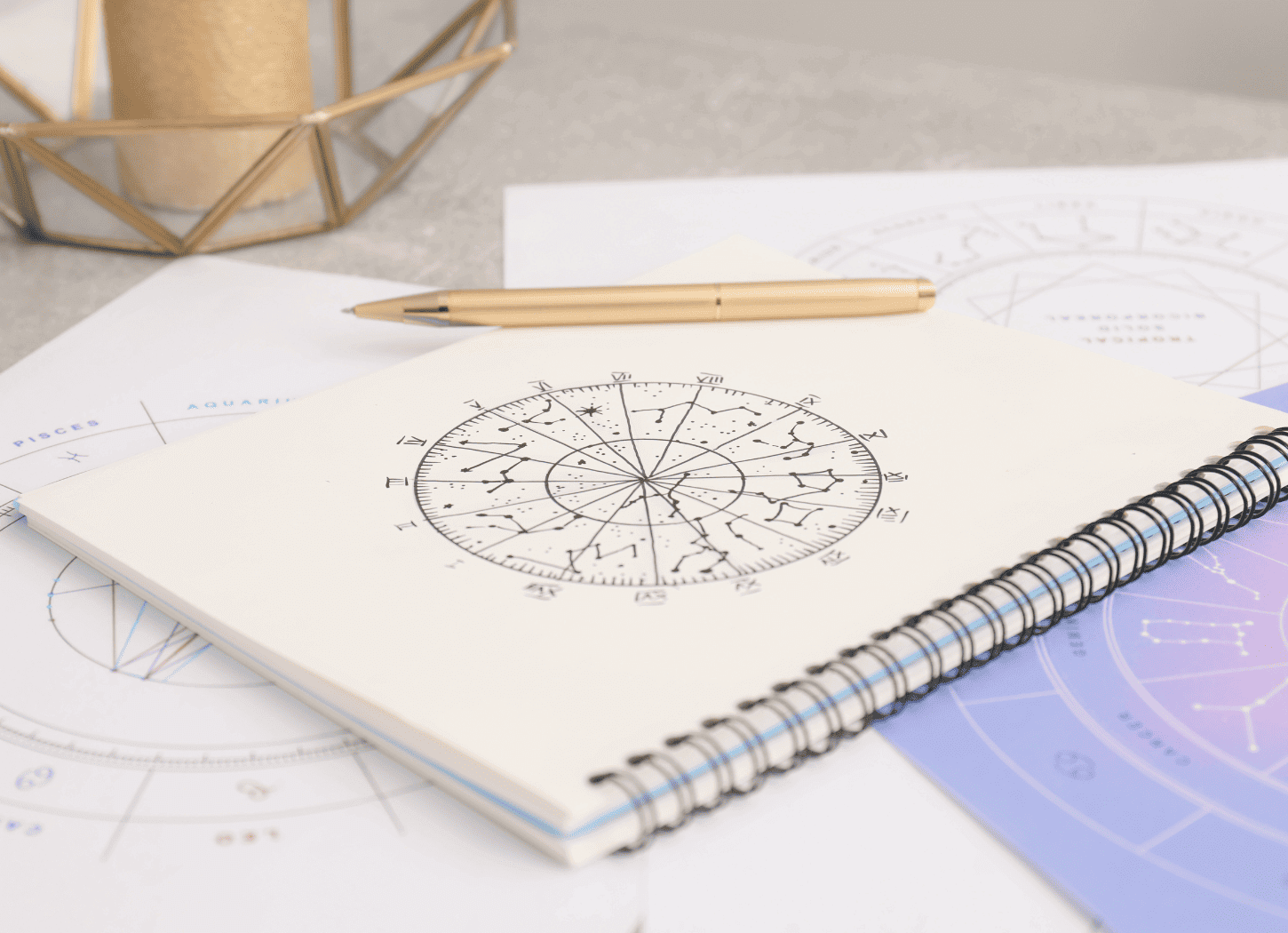 リングノートに描かれたホロスコープと、そっと添えられたゴールドのペン。占いの準備を物語ります。