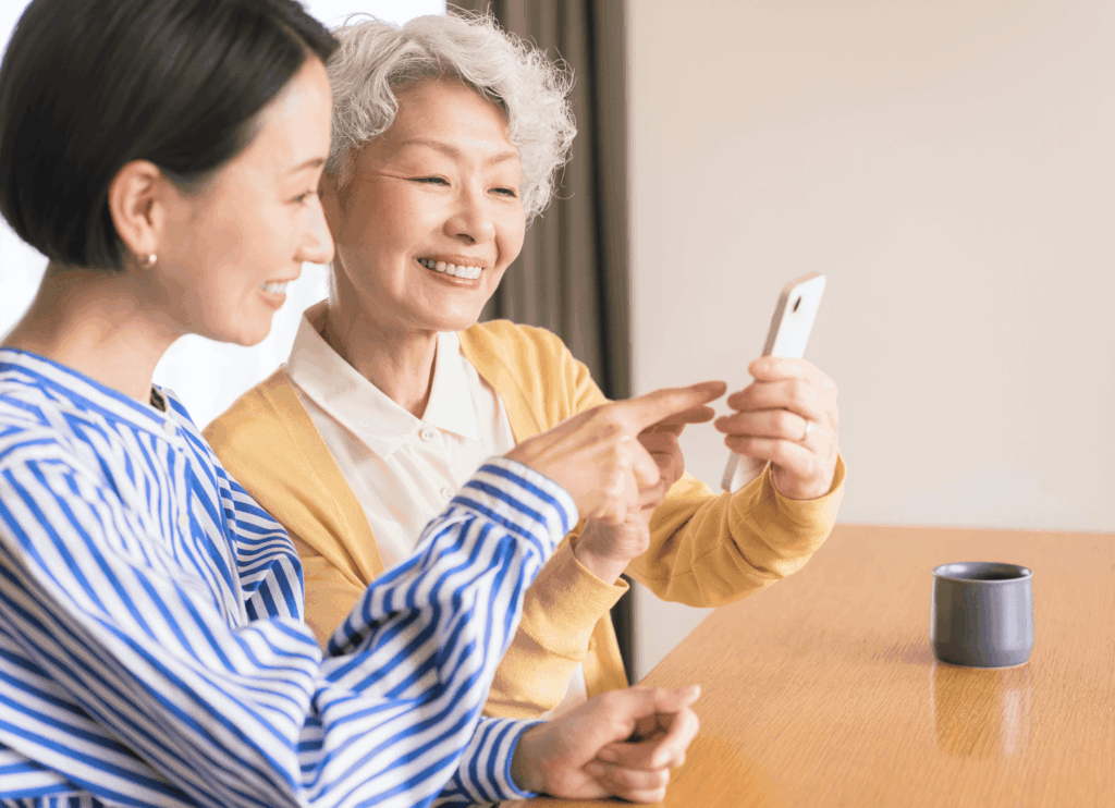 ばぁばにスマホで運動会の動画や写真を見せる女性