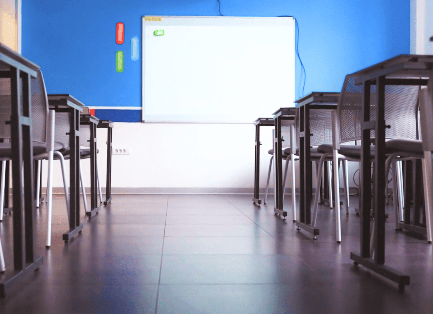 青い壁にホワイトボードがある学校の教室。机と椅子が整然と並び、高校では別れてしまった二人の「ひろみちゃん」をイメージ。