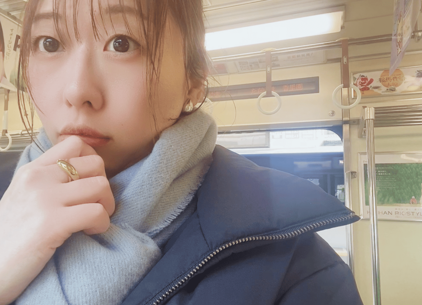 停車中の京阪電車内で座る社会事業開発ACTION代表・堀寛未。ブラックのダウンジャケットに薄いグレーのストール、指にはゴールドの指輪