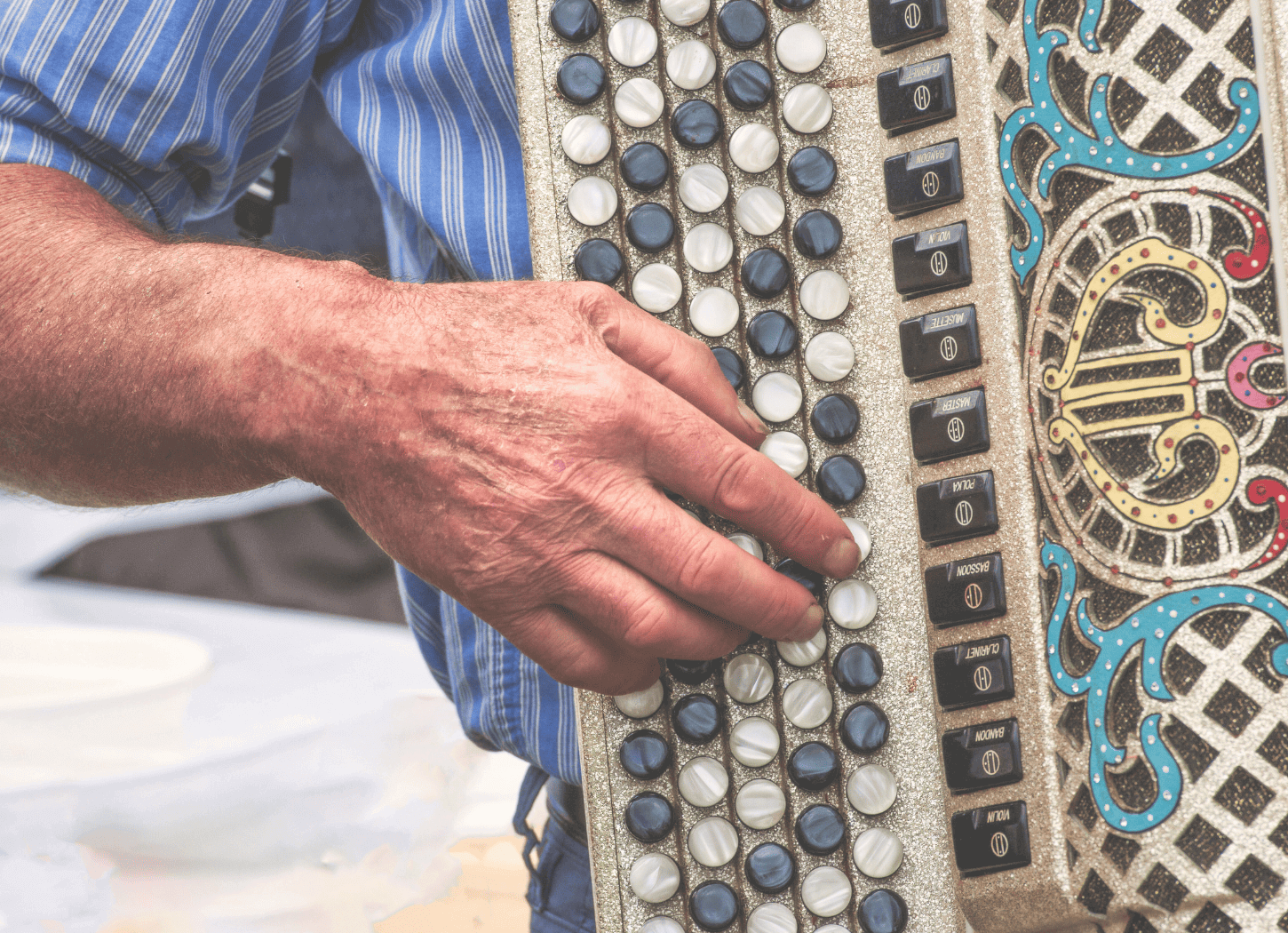 ミュゼットを演奏する男性の手元を正面から撮影。アコーディオンの鍵盤やボタンがよく見える。