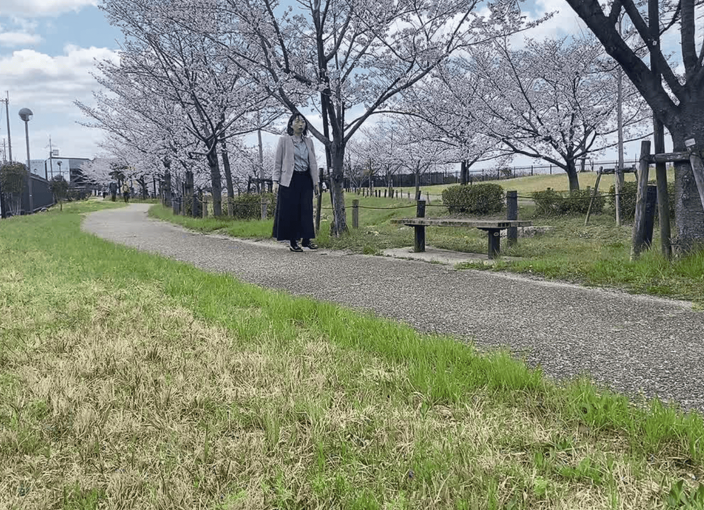 渚水みらいセンターの小道を歩く社会事業開発ACTION代表・堀寛未。木々の間を抜ける風と、小川のせせらぎが心地よい