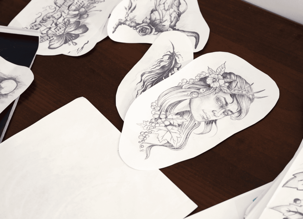 白い机の上に、描いた絵を切り取った紙片を複数並べている。バーチャルイラストレーター星奈が制作したイラストを整理している様子をイメージ