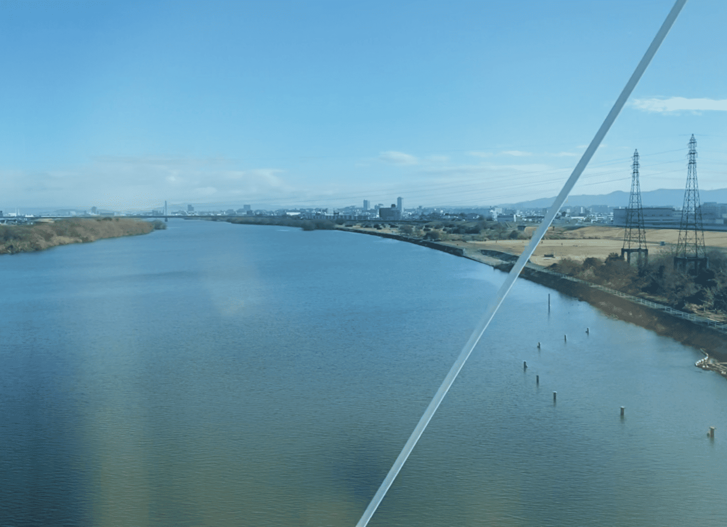 大阪モノレール『万博記念公園駅』に向かう途中に見える淀川。青空の下、緩やかなカーブを描いて遠くまで続く川の景色