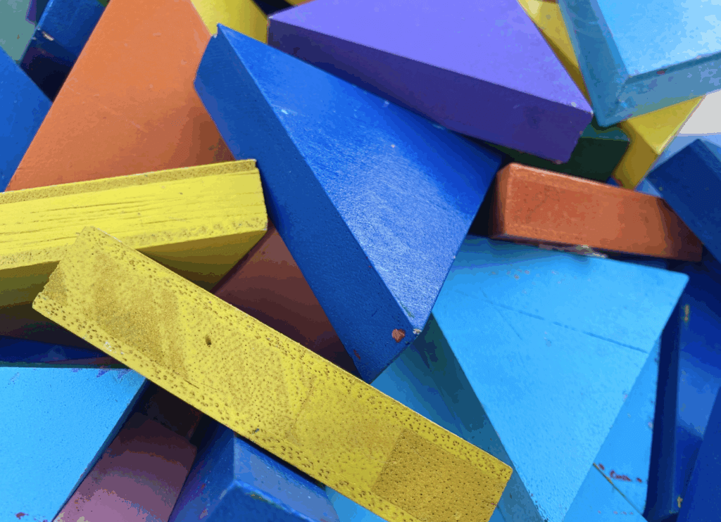 プール跡地イベントで遊ぶ、青・黄色・ピンクにペイントされた三角形の木製パズルのアップ