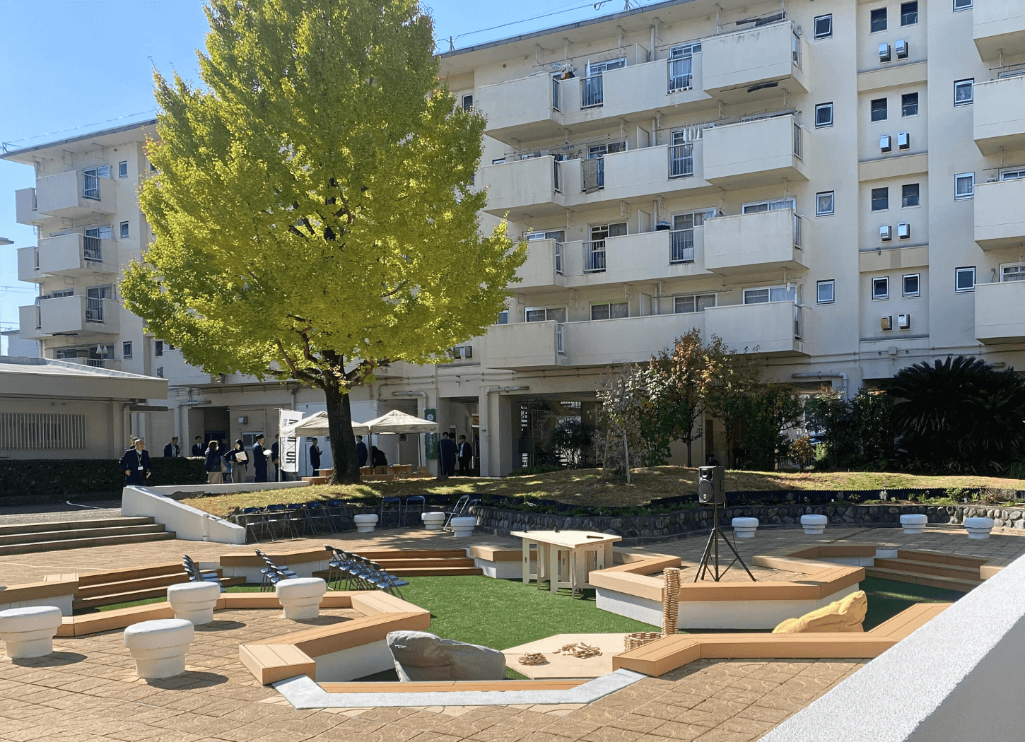 中宮第3団地のプール跡地を引きで撮影した、六角形が連なる広場と団地、青空の風景