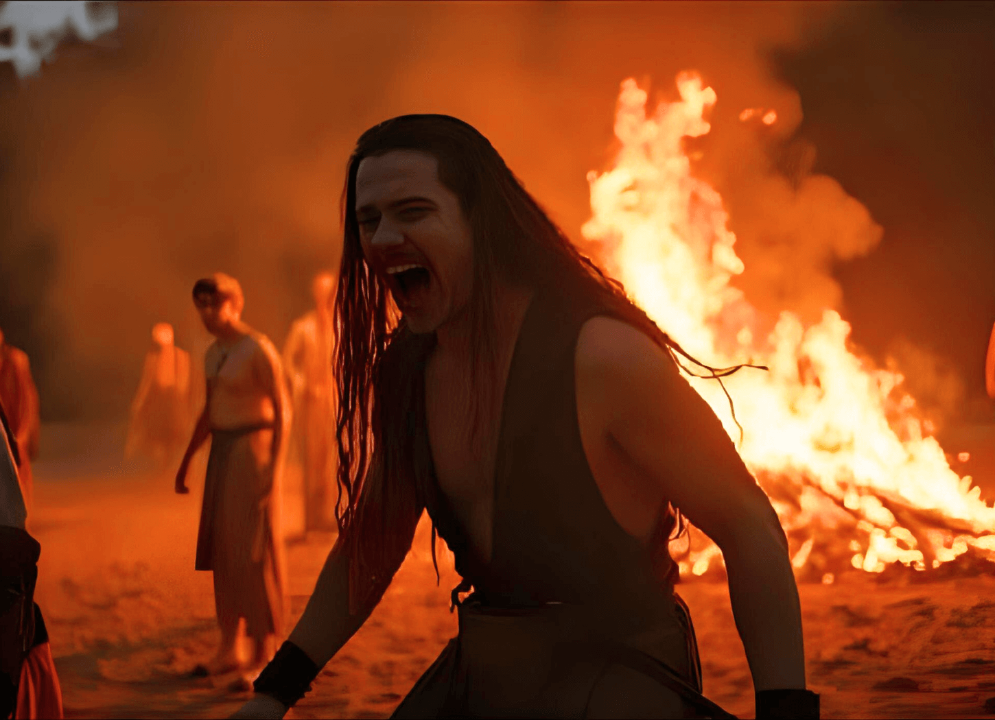 暗闇の中、燃え盛る焚き火を背に、袖のない質素な着物を着た長髪の男性が苛立ち、何かを叫んでいる。蝦夷の男性のイメージ。