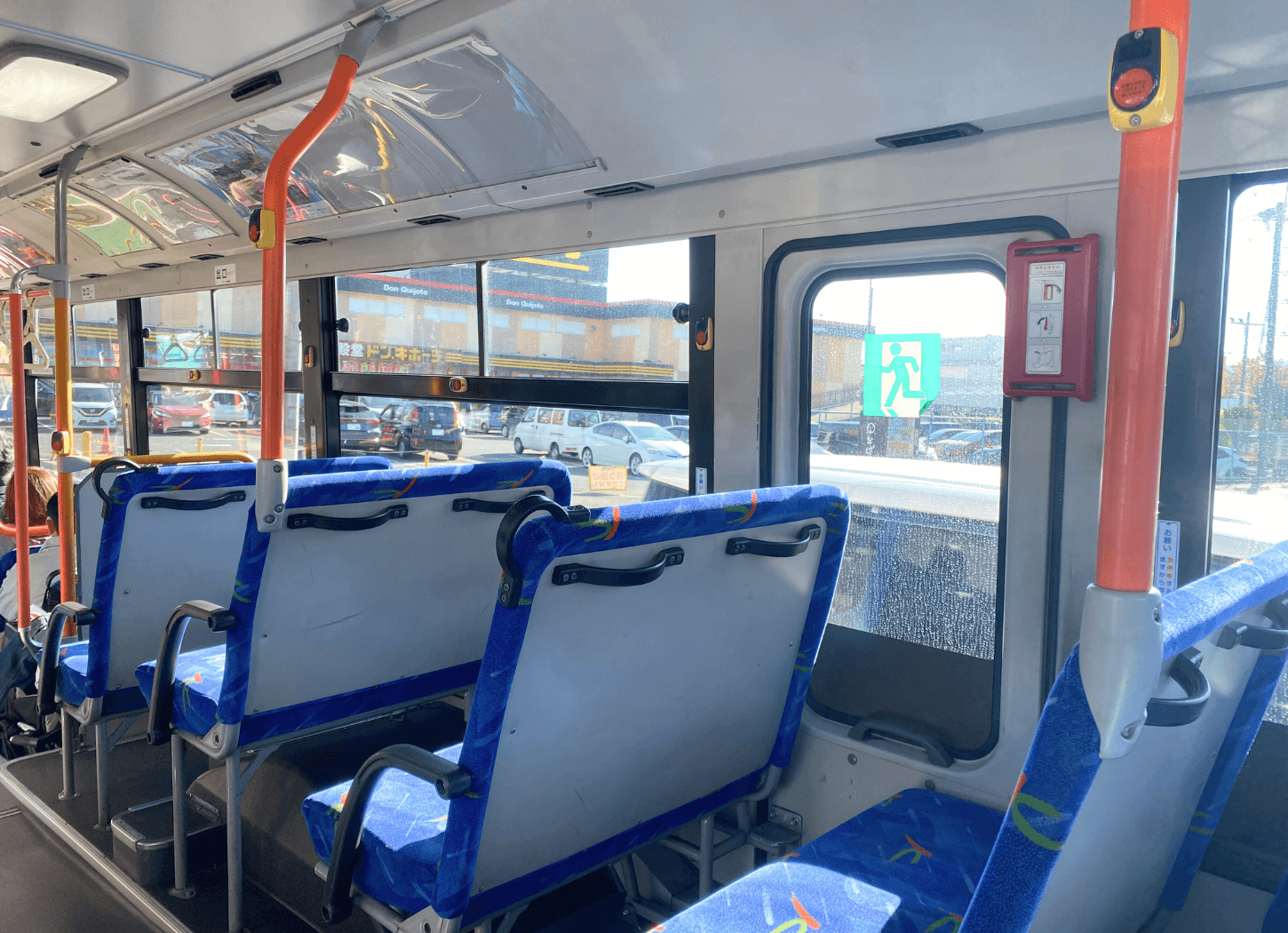 枚方市駅から山田池公園へ向かう京阪バスの車内。青い座席とオレンジ色の手すりが見え、窓の外には晴れた道路が広がっている