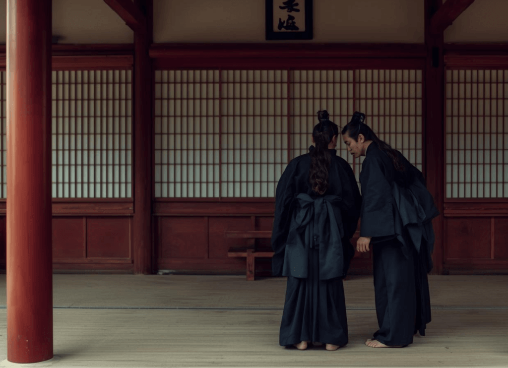 朱色の柱と障子に囲まれた廊下で、アテルイとモレの処遇について噂話をする貴族二人の想像図