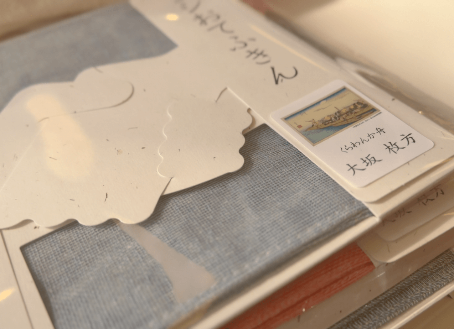 歌川広重が描いたくらわんか舟の浮世絵をモチーフにしたシールが貼られた、くらわんかファブリックのパッケージ。江戸時代の「飯くらわんか」の文化を感じさせるデザイン