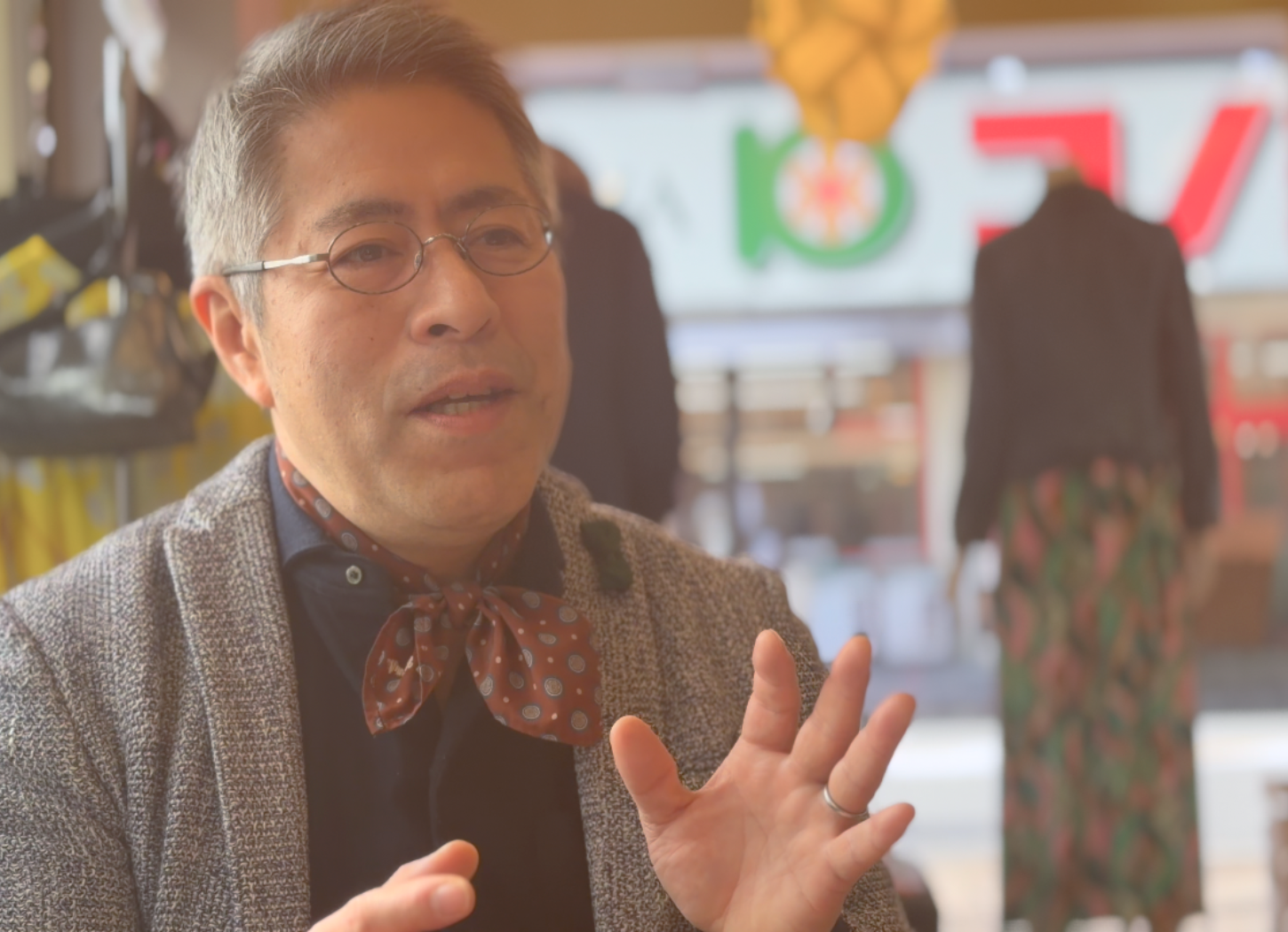 椅子に座り両手を広げながら話す、くらわんかファブリックの富江さん。真剣な眼差しで想いを語る取材風景