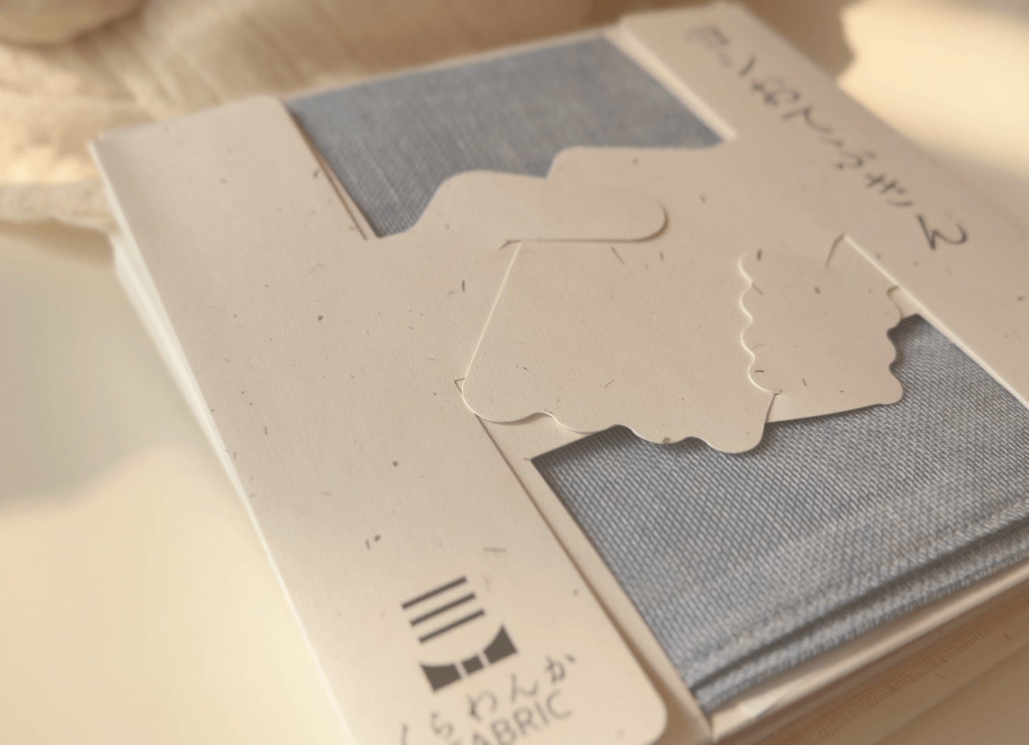 ヨシ素材で作られた「おてふきん」のギフトボックス。手と手が握手するデザインが施された、くらわんかファブリックの商品