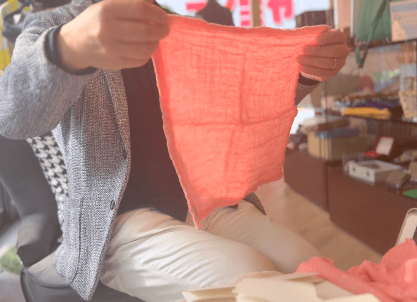 くらわんかファブリックのヨシのおてふきん(ピンク色)を広げる富江さん。三層構造で吸水性が高く、乾きやすい大判サイズの様子