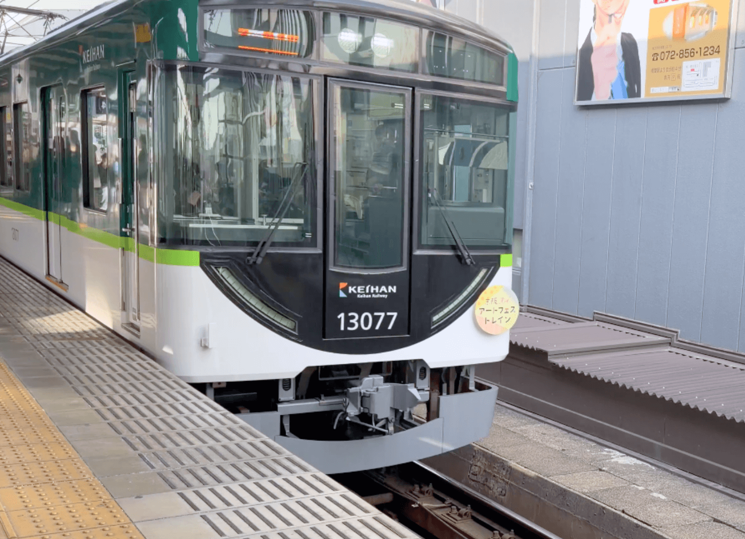 京阪電車樟葉駅ホームに停車する京阪Kidsアートフェストレイン。車両正面に「アートフェストレイン」と書かれた円形パネルが掲出されている。