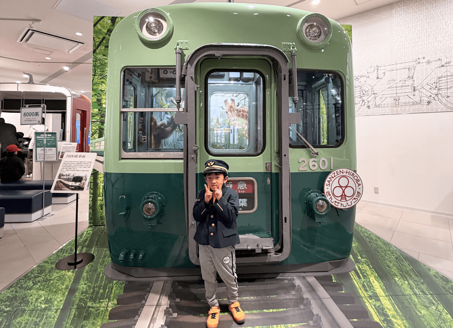 くずはモールSANZEN-HIROBAで開催された第4回京阪Kidsアートフェスの「制服でハイ！チーズ」コーナー。京阪電車の車両前で制服と制帽を着て記念撮影する子どもの様子。