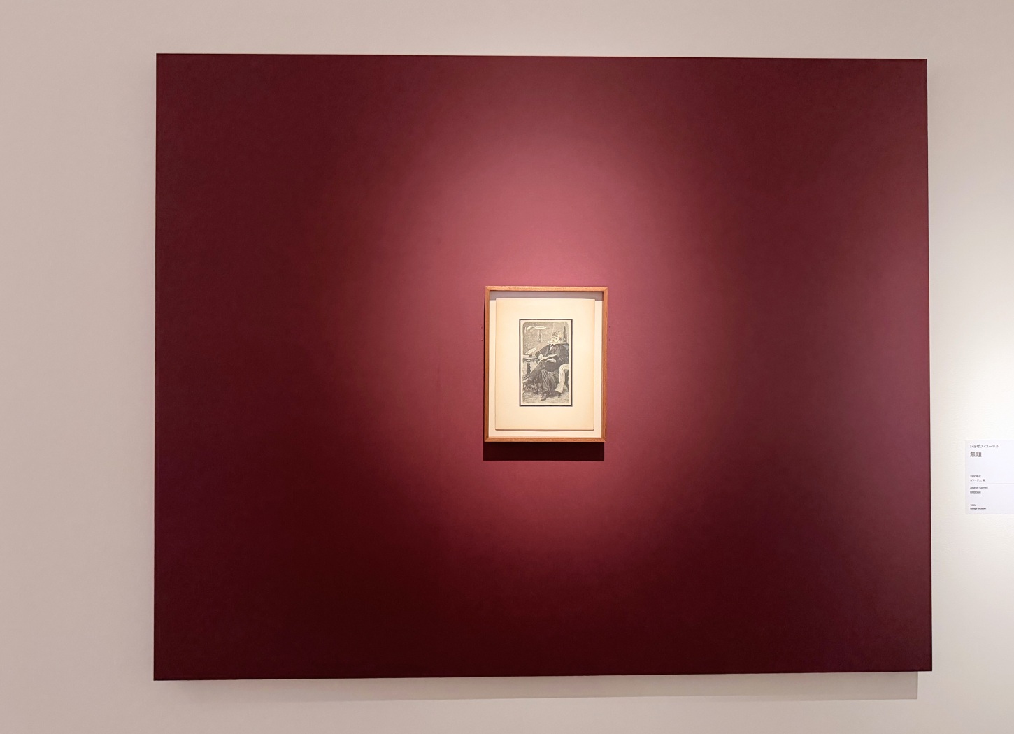 深い赤の壁面中央に小さな額装作品が展示された、中之島美術館の展示風景