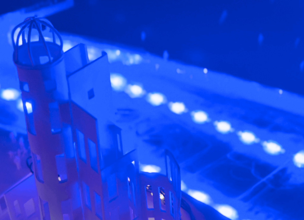 青くライトアップされた原爆ドームのミニチュアと、川のそばに集う人々の様子