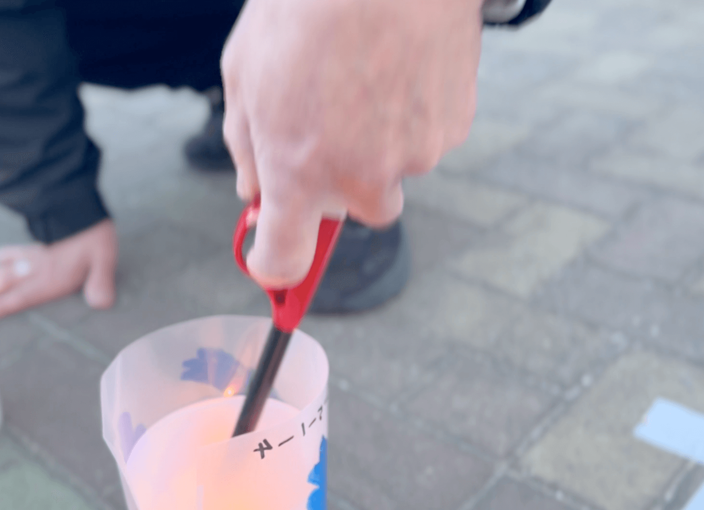 枚方市平和の燈火でキャンドルに火をつける男性の手元