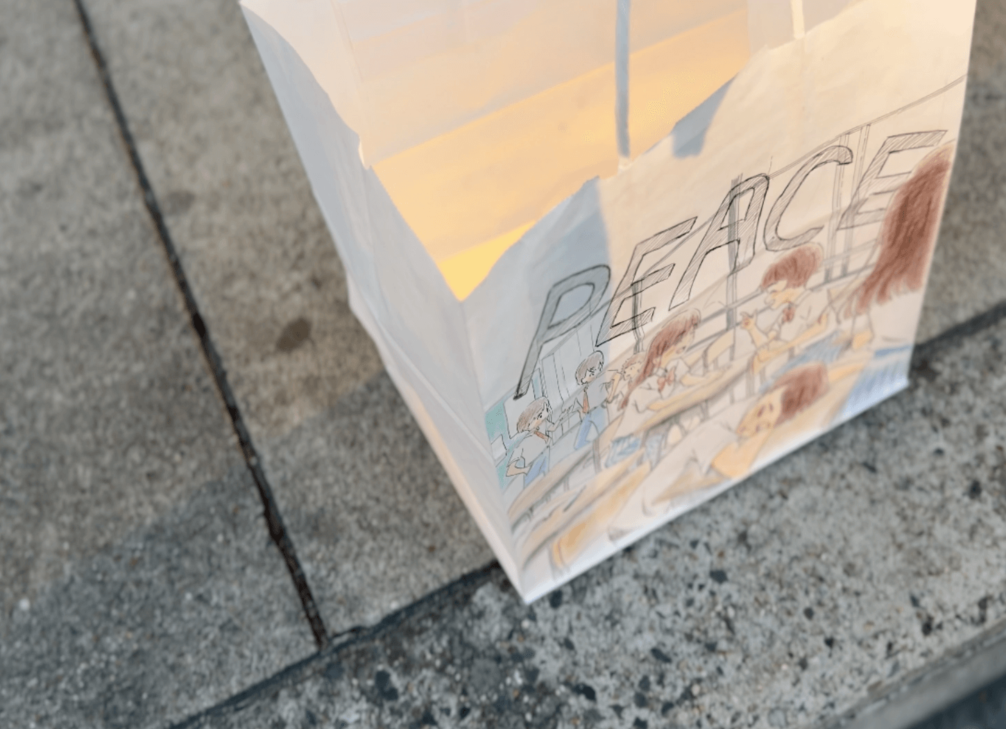 休み時間の教室の様子と「PEACE」の文字が描かれた平和のメッセージキャンドル