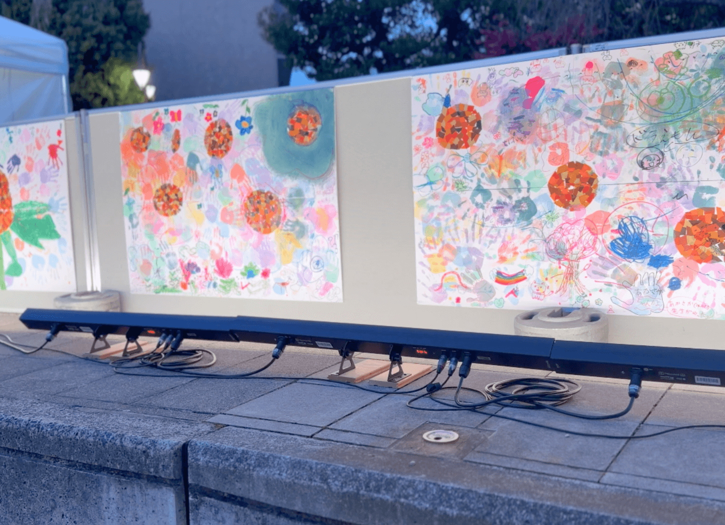 学生たちが手形で描いた平和をテーマにしたカラフルなイラストパネルが壁に貼られている様子