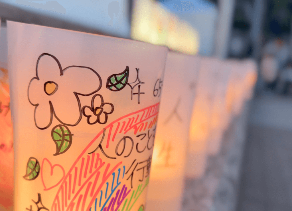 虹や白い花の絵とともに平和へのメッセージが書かれたキャンドルのアップ