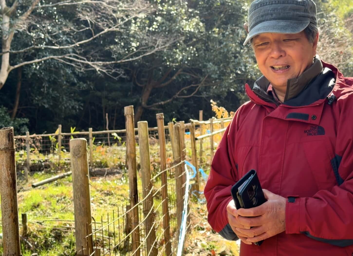 穂谷の里山で、スマートフォンを手に立つ石野さん