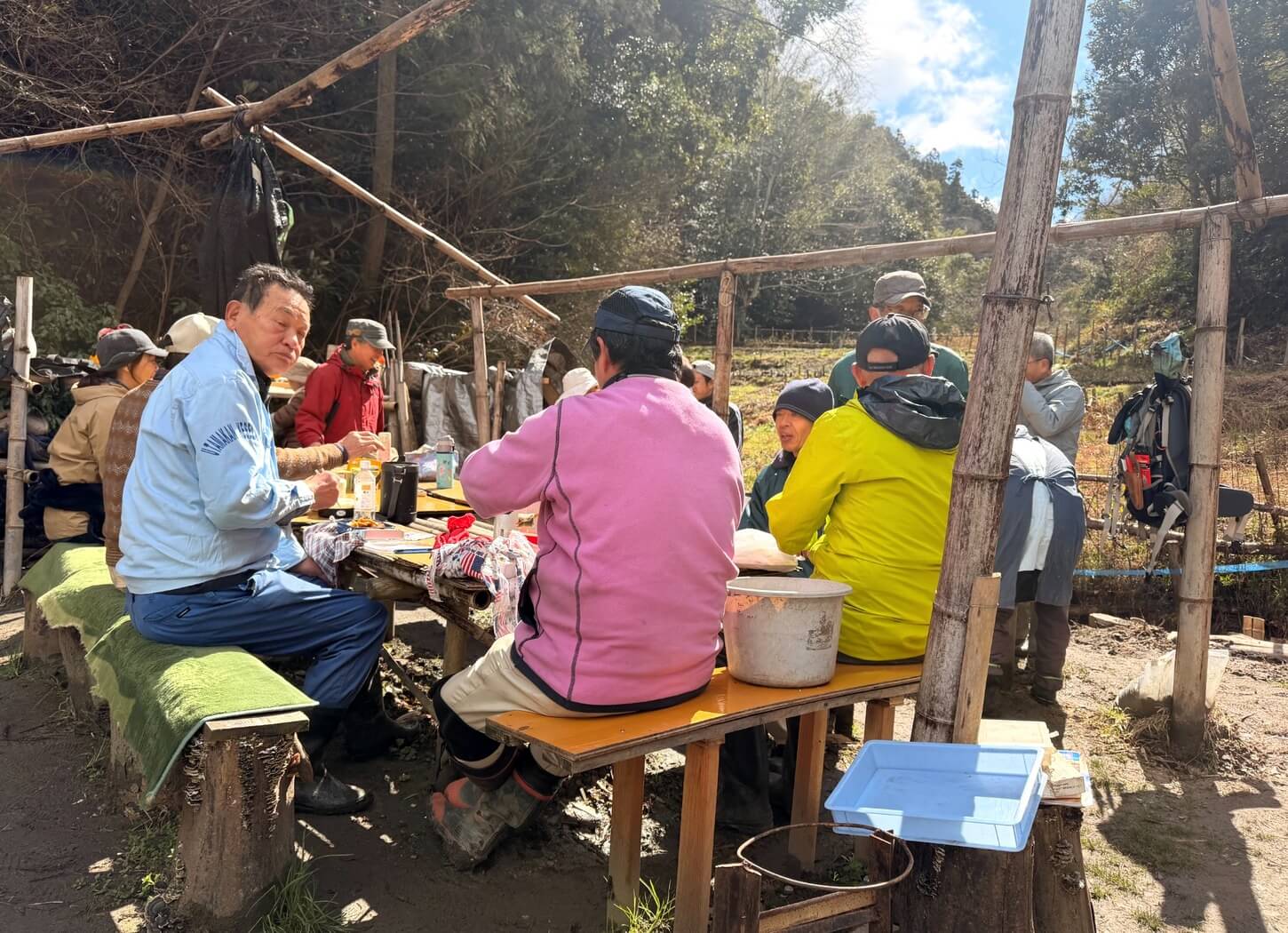 穂谷の里山で昼食を囲み、会員たちが談笑する様子