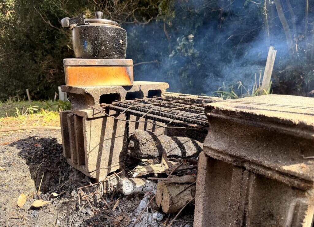 小屋のそばで湯を沸かす薪火のかまど