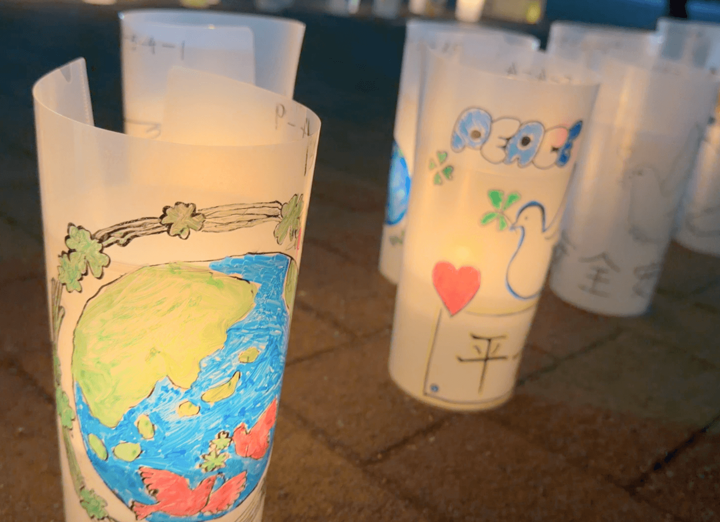 ニッペパーク岡東中央で行われた「枚方市平和の燈火」で、平和への願いが描かれたキャンドルランタンが夜の会場に並んでいる